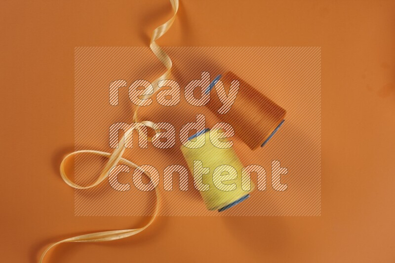 A yellow collection of sewing and tailoring tools arranged on a orange background