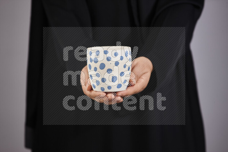 A woman in black abaya holding different pottery essentials in different positions