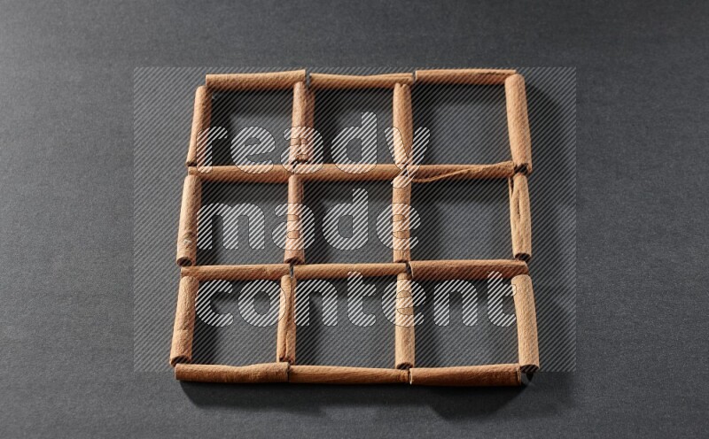 9 empty squares of cinnamon sticks on black flooring