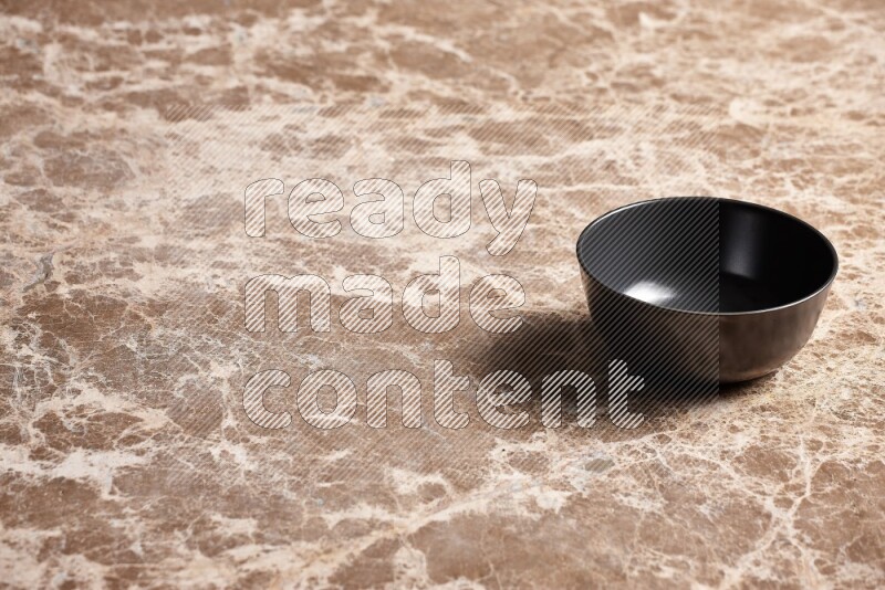 A black ceramic bowl on beige marble background