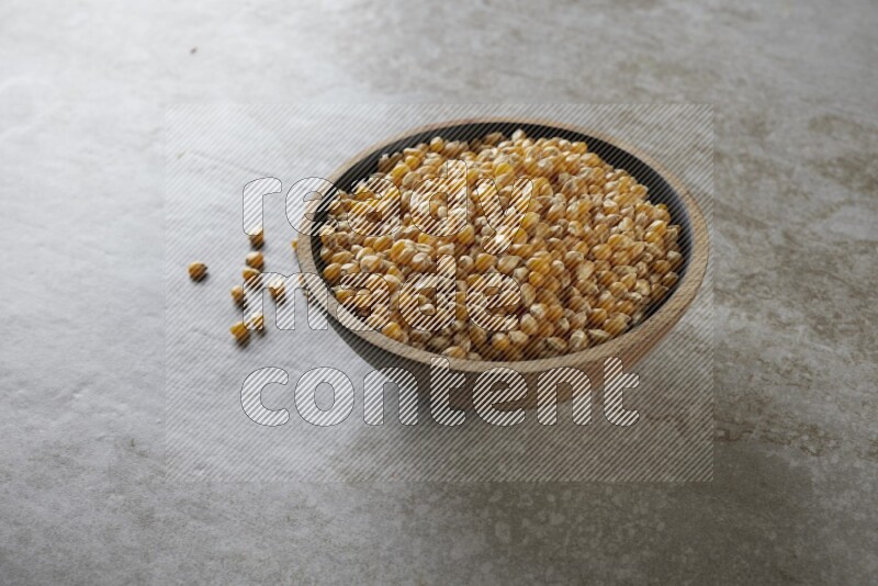 corn kernel in a wooden bowl on a grey textured countertop