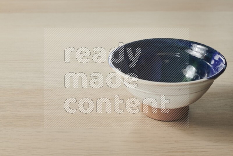 A multicolored pottery bowl on light wooden background