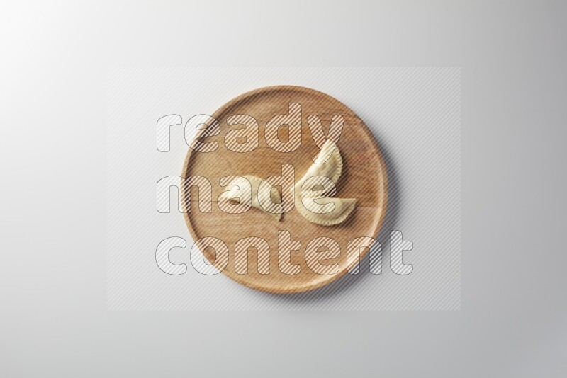 Three Sambosas on a wooden round plate on a white background