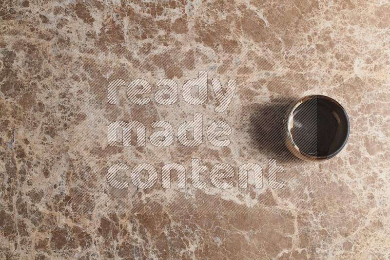 A multicolored pottery bowl on beige marble background