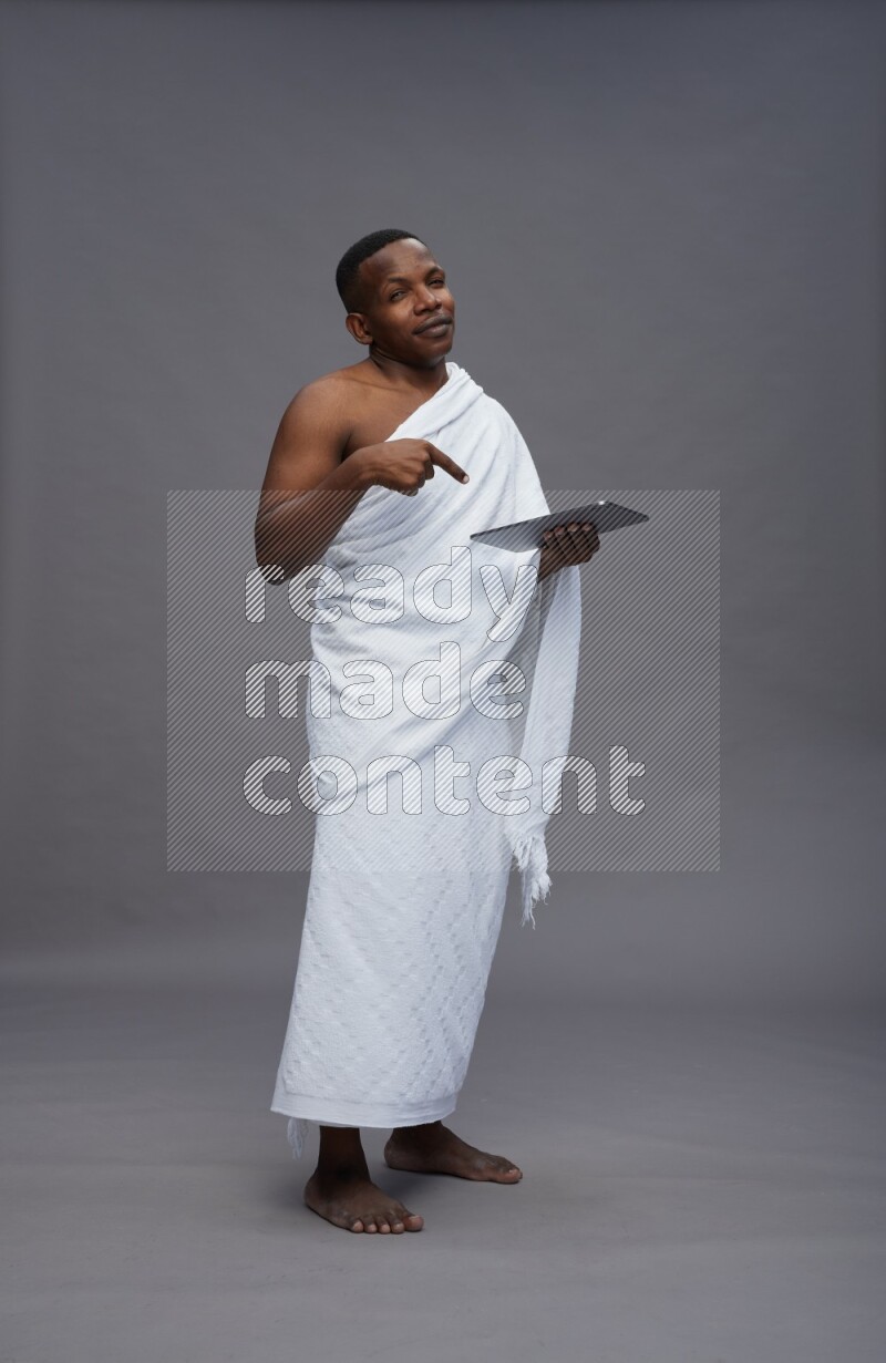 A man wearing Ehram Standing working on tablet on gray background