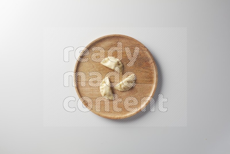 Three Sambosas on a wooden round plate on a white background