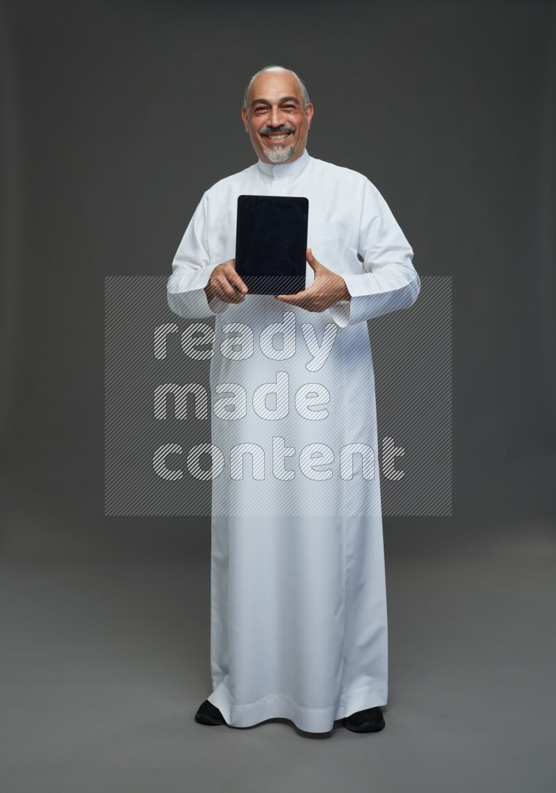 Saudi man without shomag Standing working on tablet on gray background