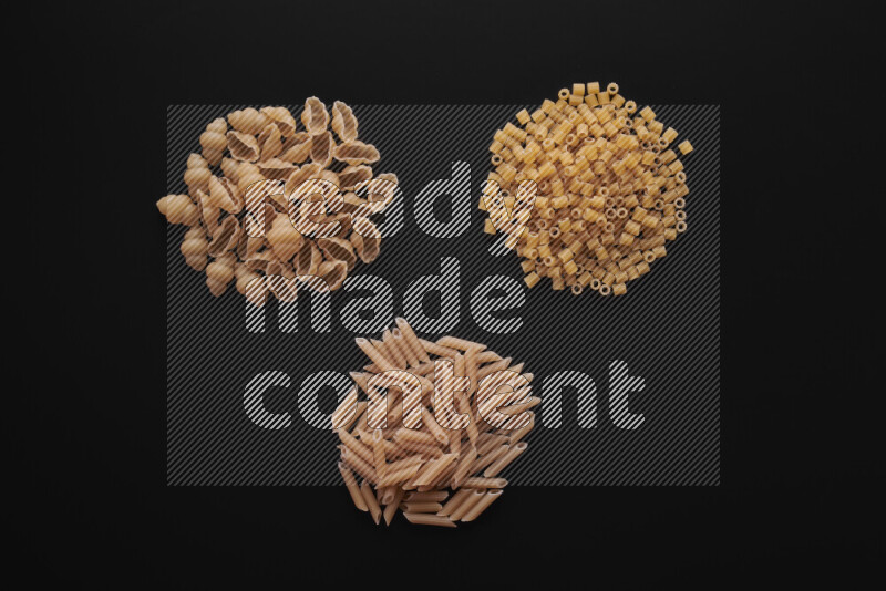 Different pasta types in bunches on black background