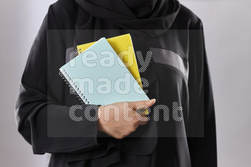 A woman in abaya holding books and a board in different positions (back to school)