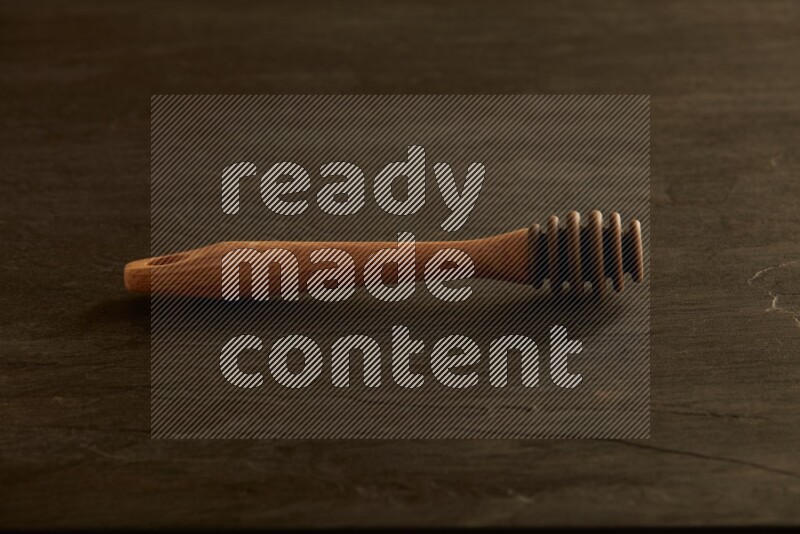 Wooden honey dipper on black slate background
