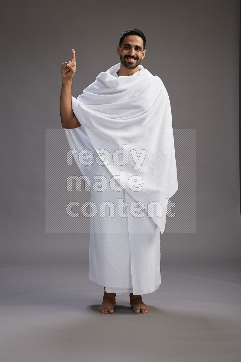 A man wearing Ehram Standing Interacting with the camera on gray background