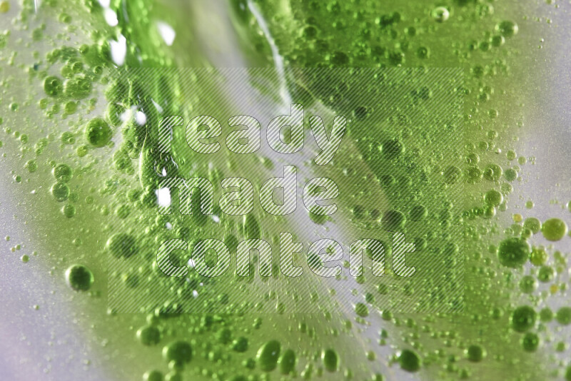Close-ups of abstract green watercolor drops on oil Surface on white background