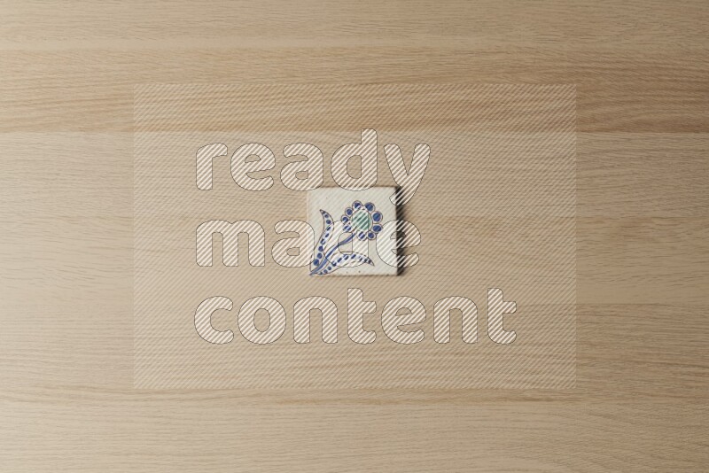 A decorative pottery coaster on light wooden background