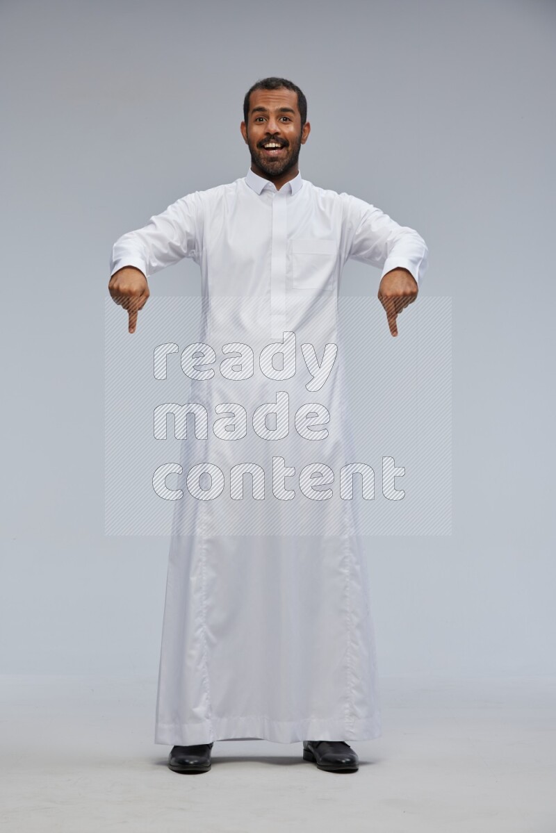 Saudi man Wearing Thob standing interacting with the camera on Gray background