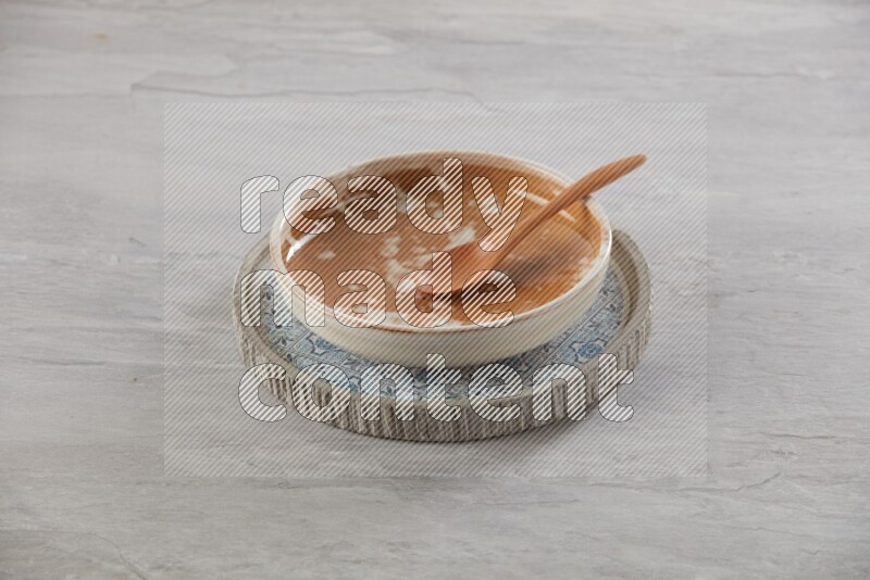 multi color pottery round dish on top of multi color round ceramic plate and spoon, on grey textured countertop