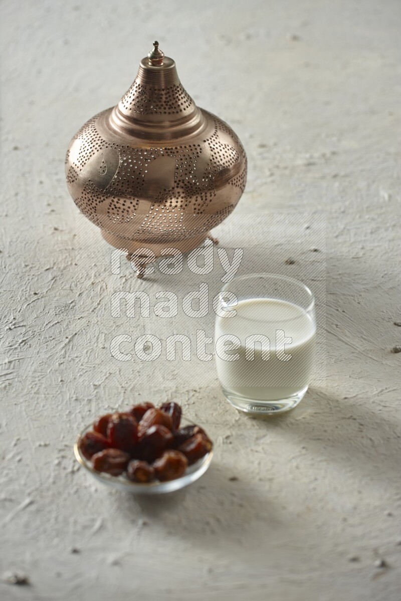 A golden lantern with different drinks, dates, nuts, prayer beads and quran on textured white background
