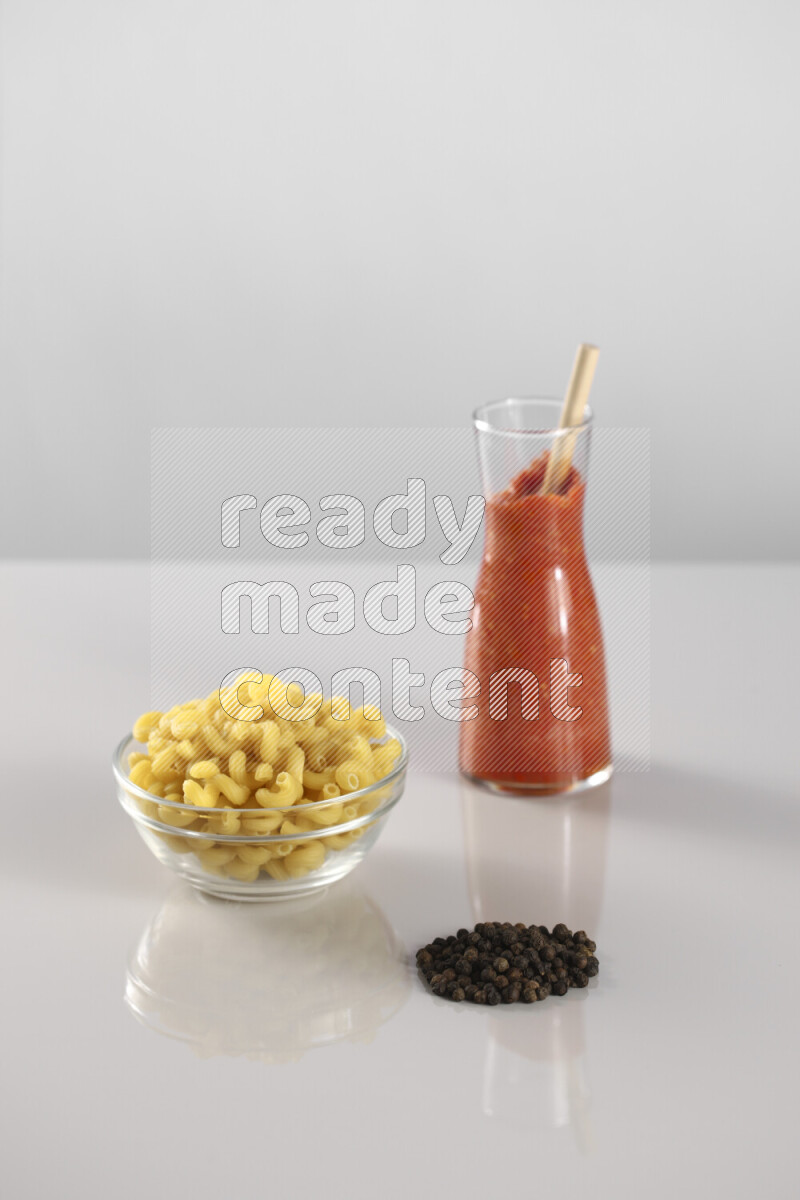 معكرونة مع صلصة طماطم مع مكونات متنوعة من الطماطم والثوم والريحان والفلفل الأحمر والفلفل الأسود والفلفل الأبيض وأوراق الغار والهيل وسنابل القمح على خلفية رمادية