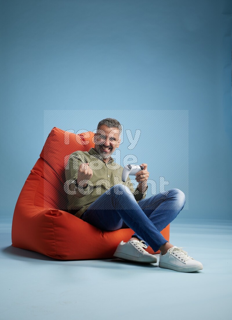 A man sitting on an orange beanbag and gaming with joystick