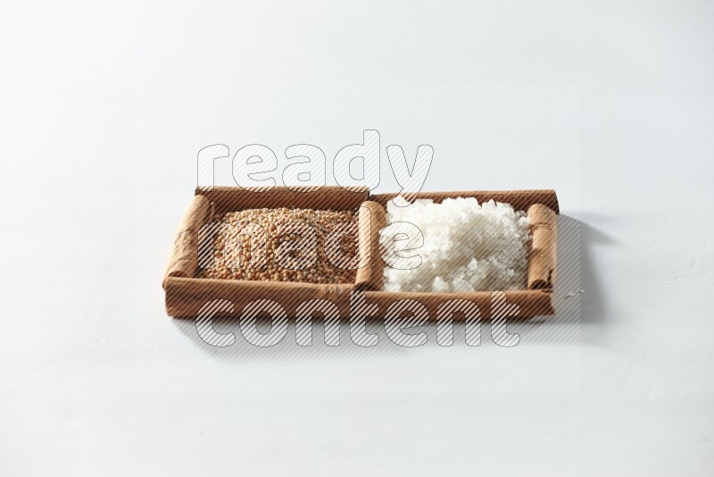 2 squares of cinnamon sticks full of mustard seeds and white salt on white flooring