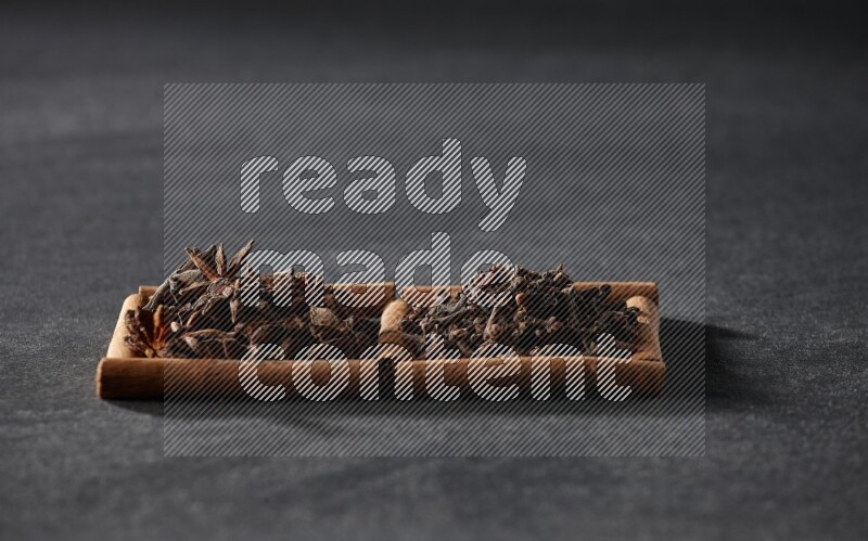 2 squares of cinnamon sticks full of star anise and cloves on black flooring