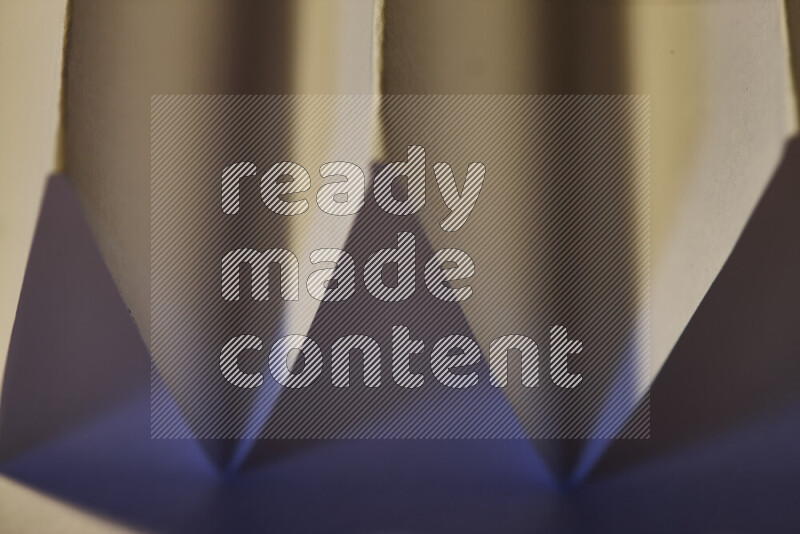 A close-up abstract image showing sharp geometric paper folds in blue gradients and warm tones