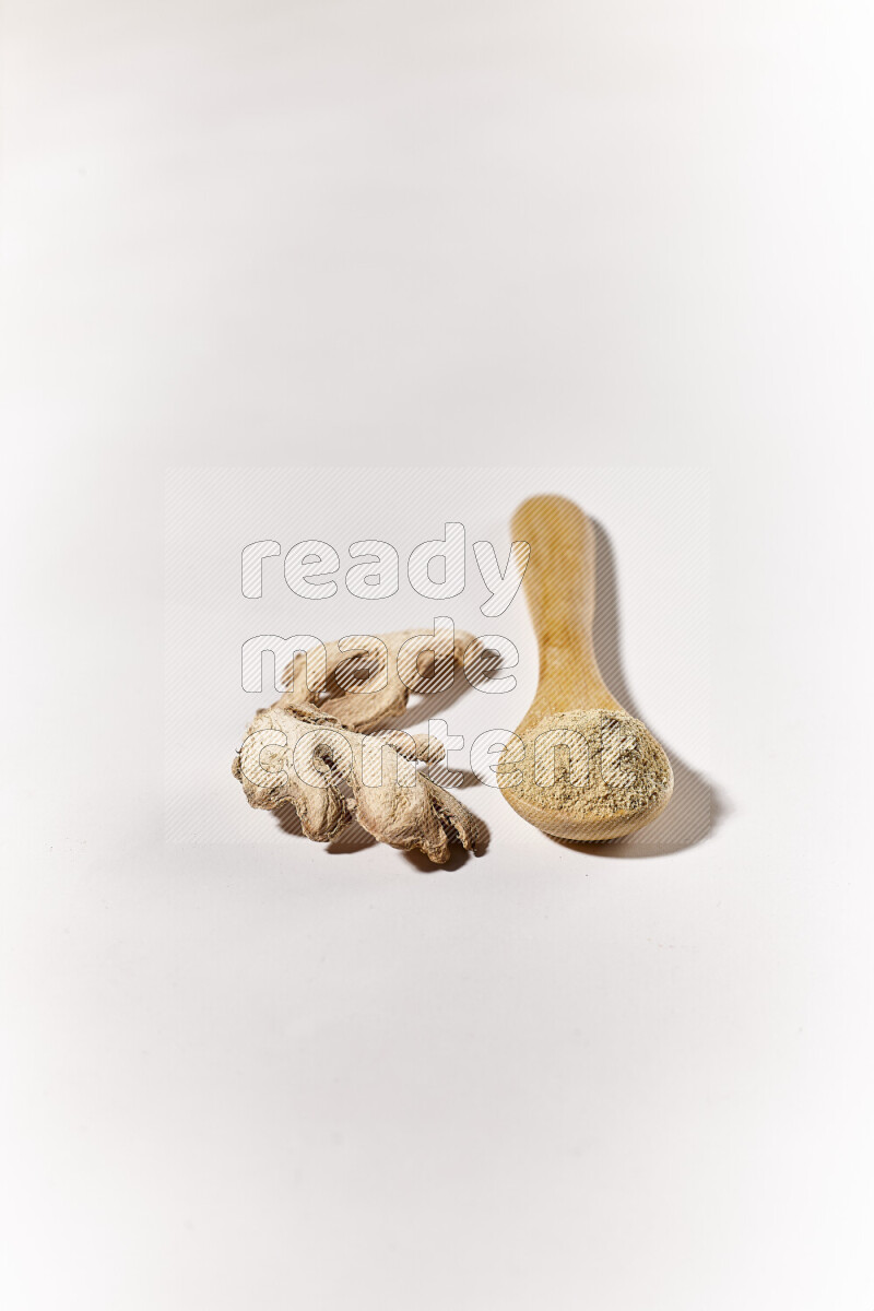 A wooden spoon full of ground ginger powder on white background