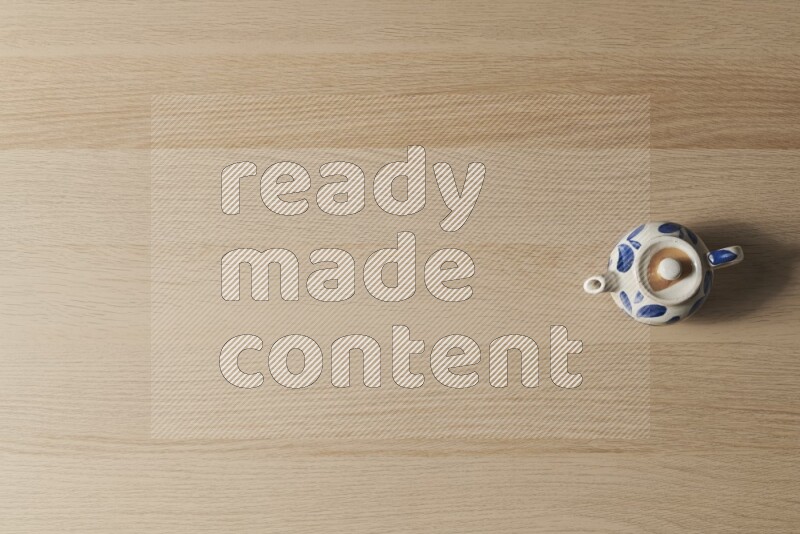 A pottery teapot on light wooden background