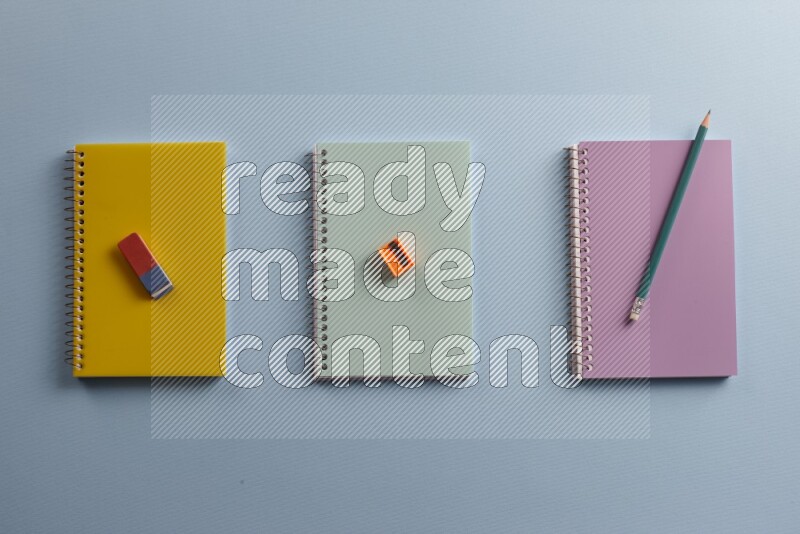 Multicolored notebooks with different school supplies on blue background