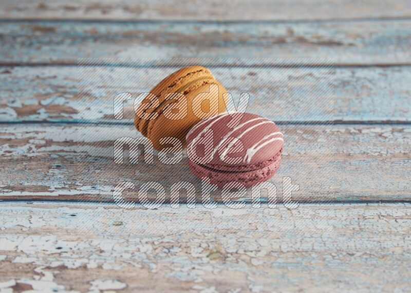 45º Shot of of two assorted Brown Irish Cream, and Red Poppy Flower macarons  on light blue background