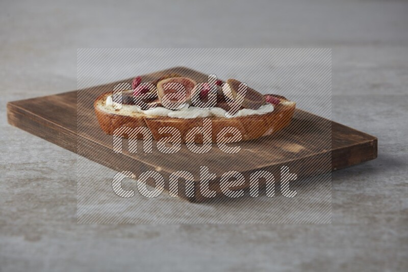 figs slices  with cream cheese on toasted sourdough slice on a wooden board on textured grey background