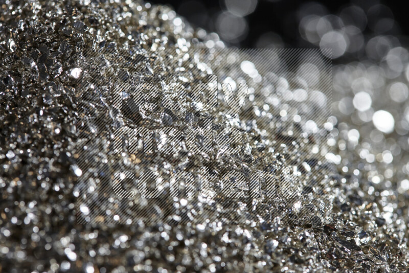 Silver shimmering fragments of glass scattered on a black background