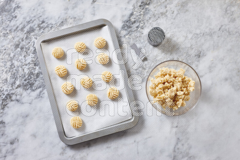 كحك خطوة بخطوة بمكوناته سمن، سكر، دقيق، سمسم، خميرة، ماء ونكهة الكحك على خلفية رخام رمادي