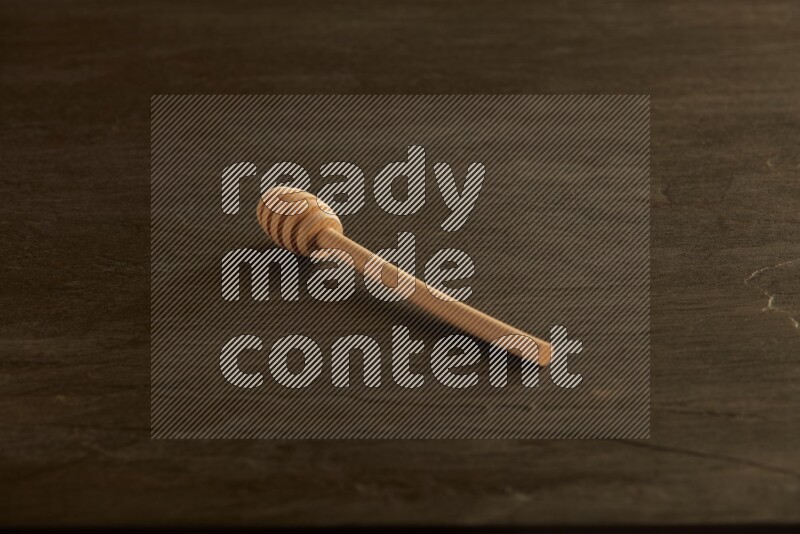 Wooden honey dipper on black slate background