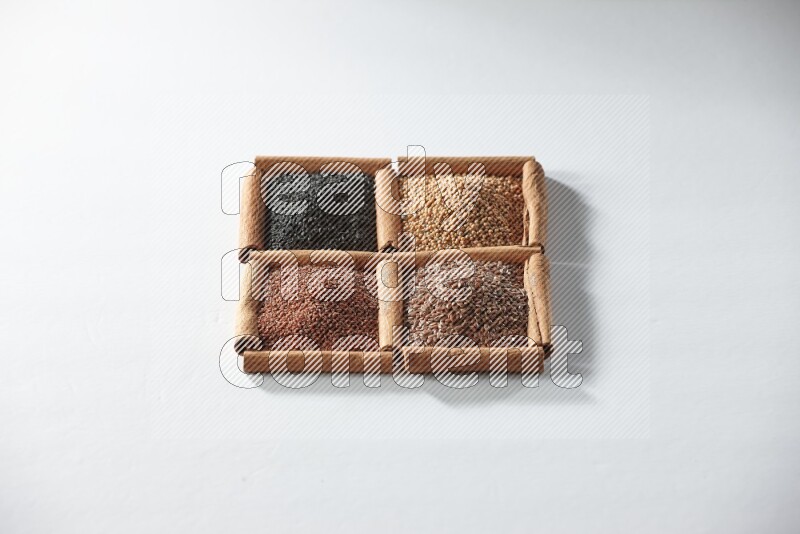 4 squares of cinnamon sticks full of black seeds, mustard seeds, flaxseeds and garden cress on white flooring