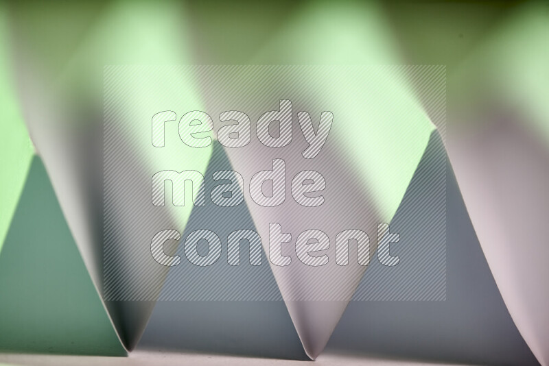 A close-up abstract image showing sharp geometric paper folds in white and green gradients