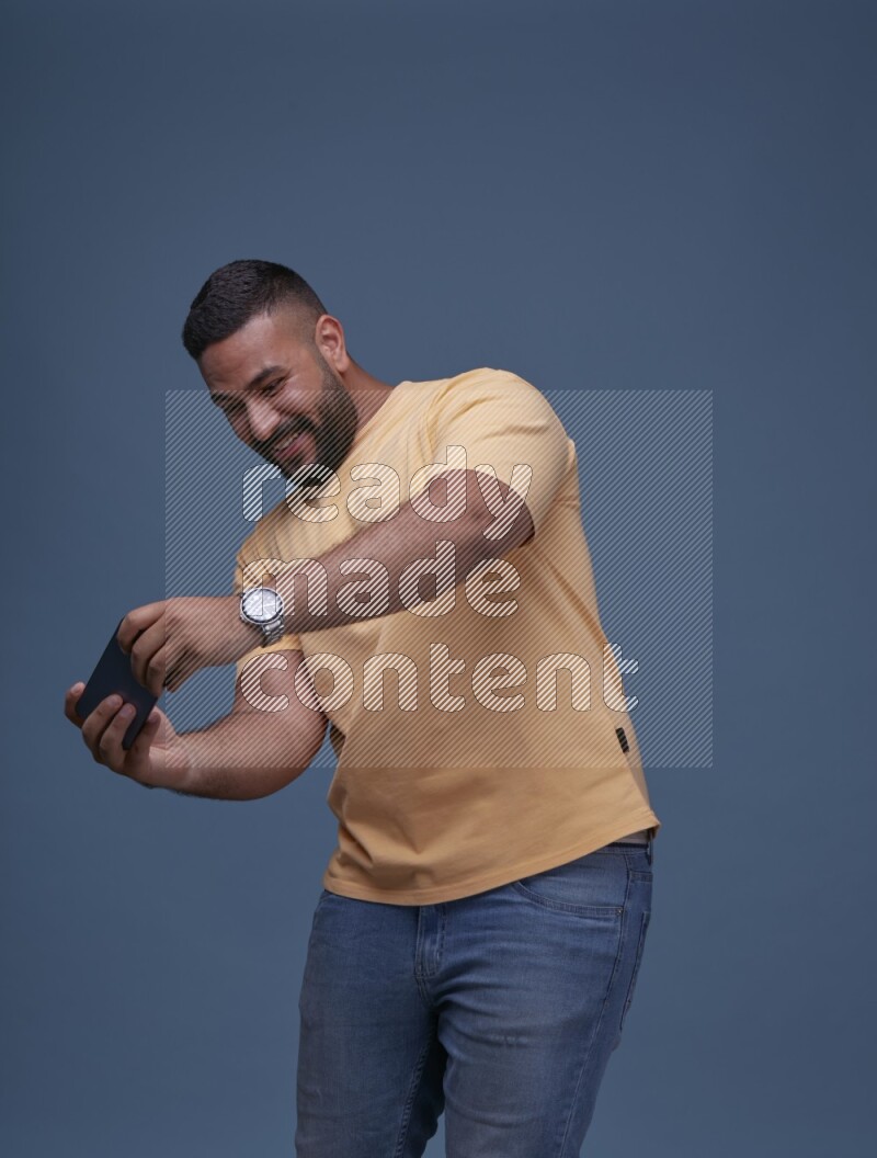 A man Playing Games on Smartphone on Blue Background wearing Orange T-shirt