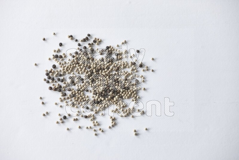 حبوب الفلفل المختلطة السوداء والبيضاء على أرضية بيضاء