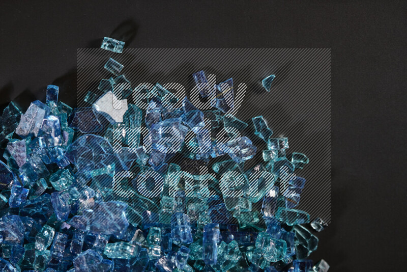 Transparent blue fragments of glass scattered on a black background