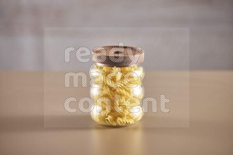 Raw pasta in glass jars on beige background