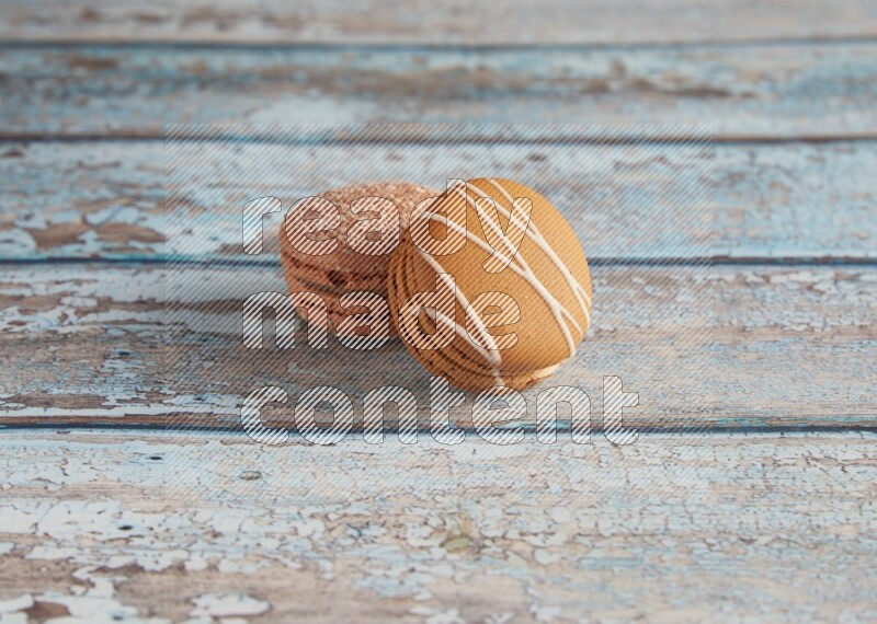 45º Shot of of two assorted Brown Irish Cream, and Brown Hazelnuts macarons  on light blue background