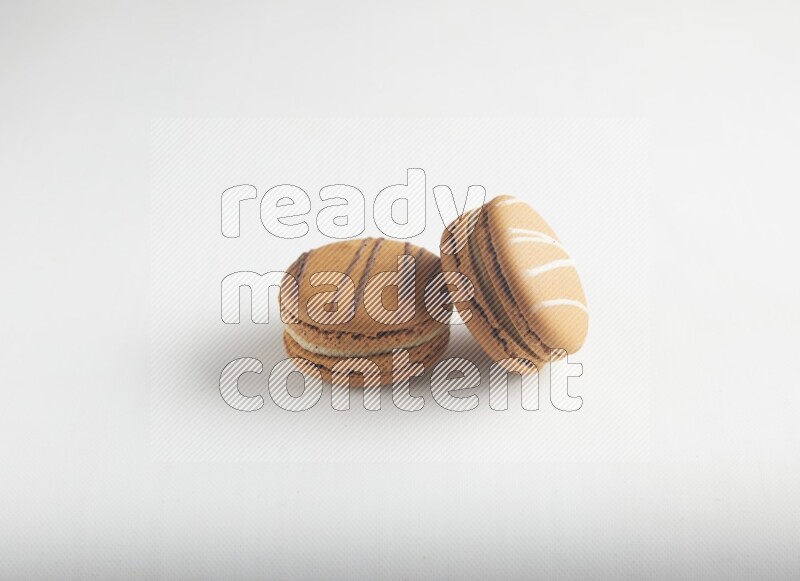 45º Shot of of two assorted Brown Irish Cream, and light brown  Almond Cream macarons on white background