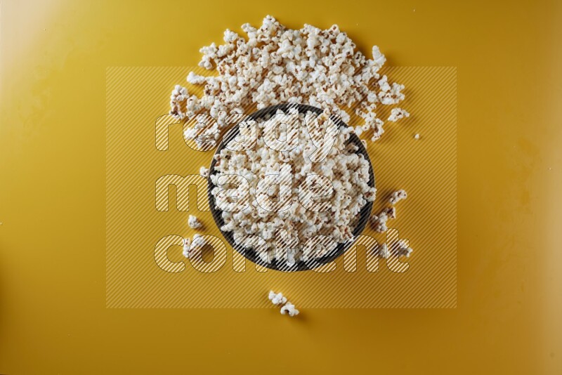 A copper ceramic bowl full of popcorn with popcorn beside it on a yellow background in different angles