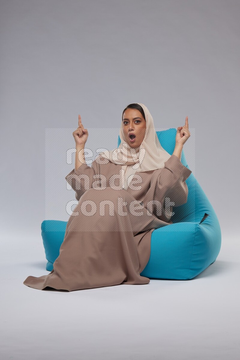 A woman sitting on a blue beanbag and interacting with the camera
