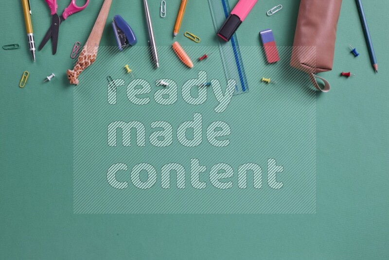 Different school supplies on green background