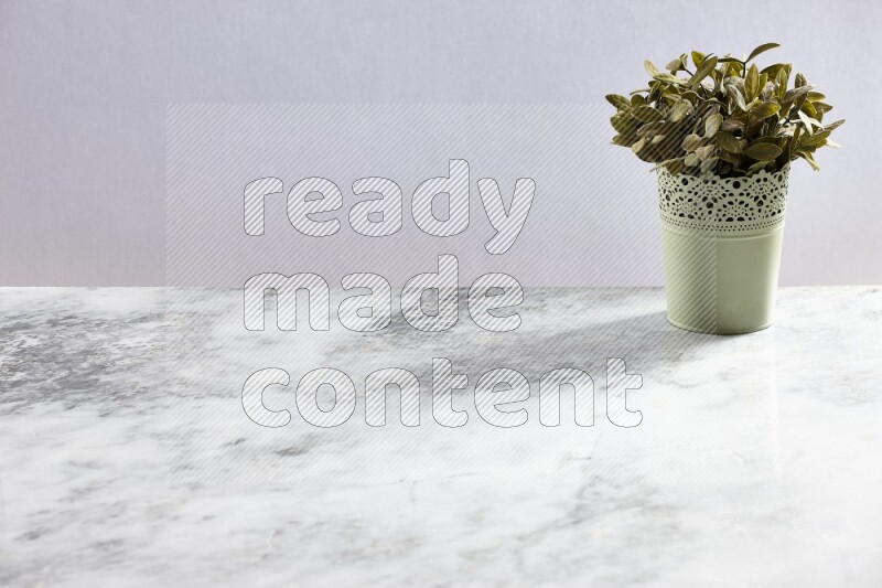 Artificial plant in green decorative pot on grey marble background