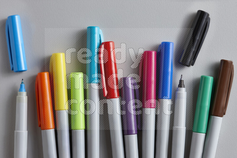 An arrangement of coloring pens in different colors on grey background