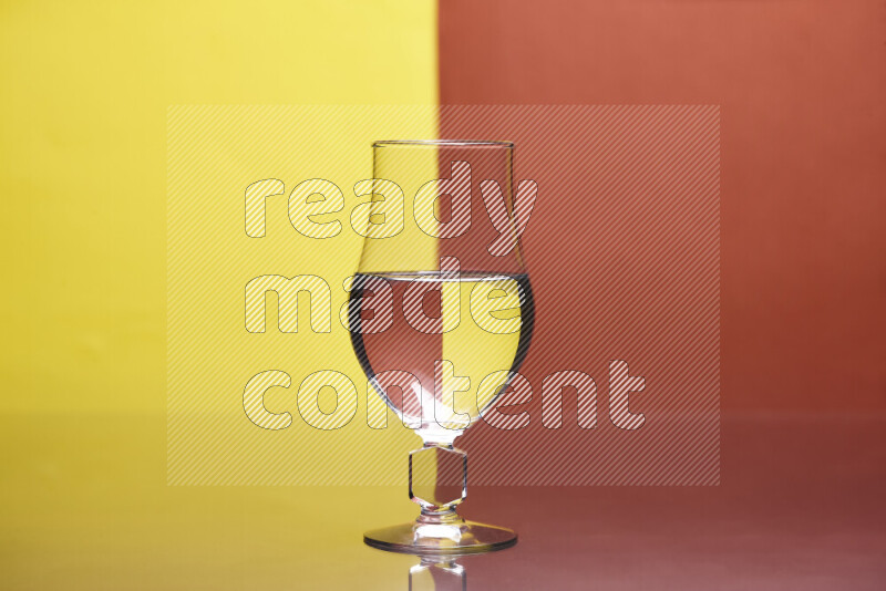 The image features a clear glassware filled with water, set against yellow and dark orange background