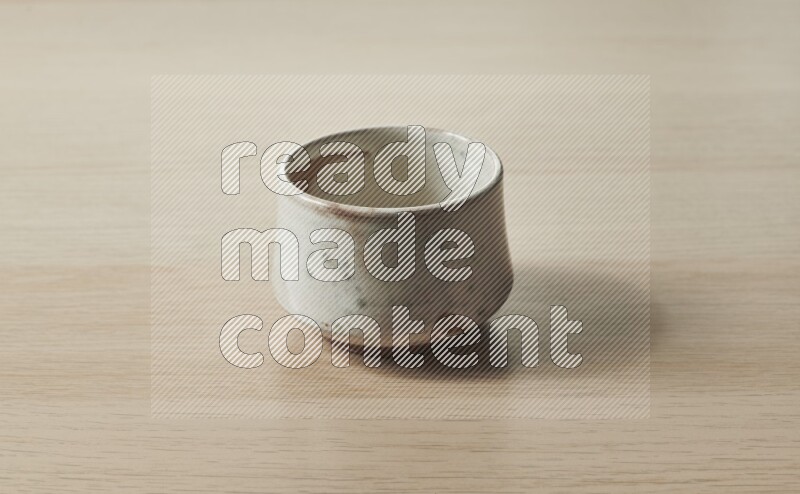 A beige pottery bowl on light wooden background