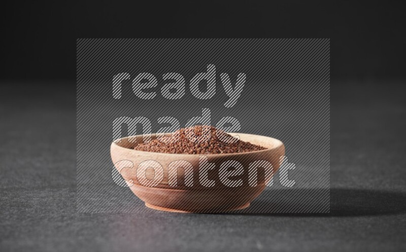 وعاء خشبي ممتلئ ببذور حب الرشاد علي خلفية سوداء