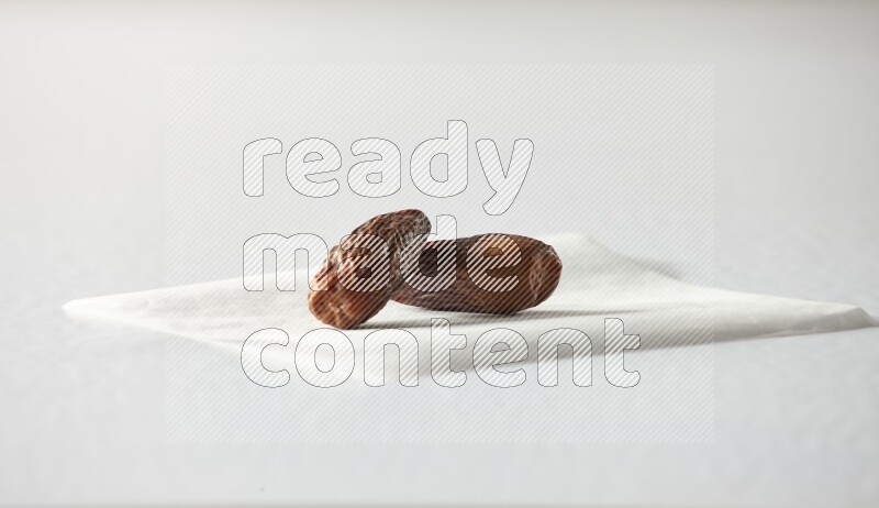 Two dried dates on a piece of paper on a white background in different angles